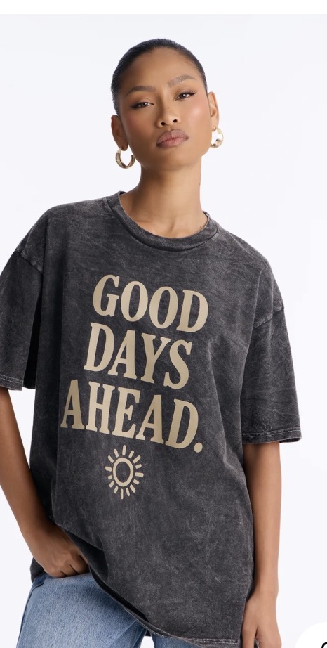 Model wearing a charcoal mineral-wash oversized tee with a sand-toned Good Days Ahead sun graphic
